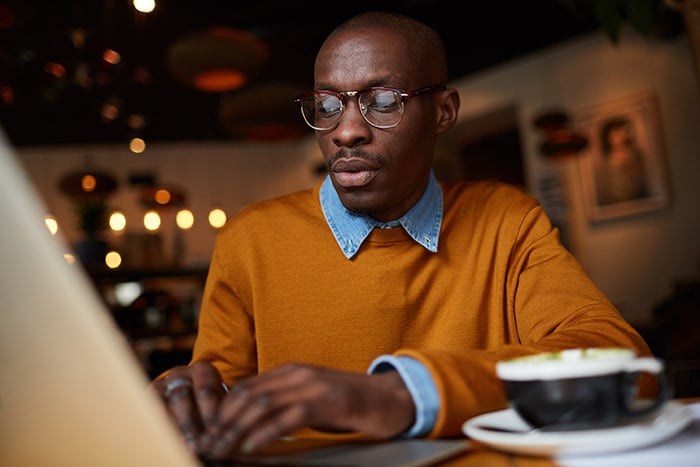 Man at a laptop thinking about the history of freelancing