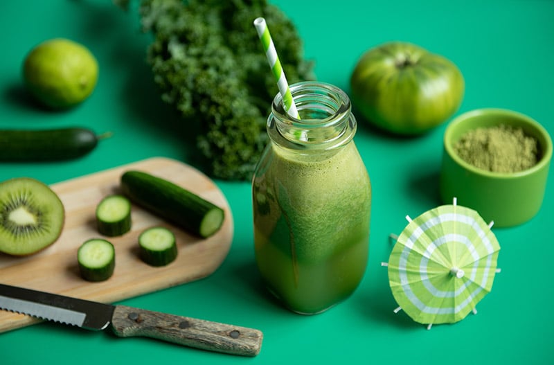 Green vegetable smoothie on green background